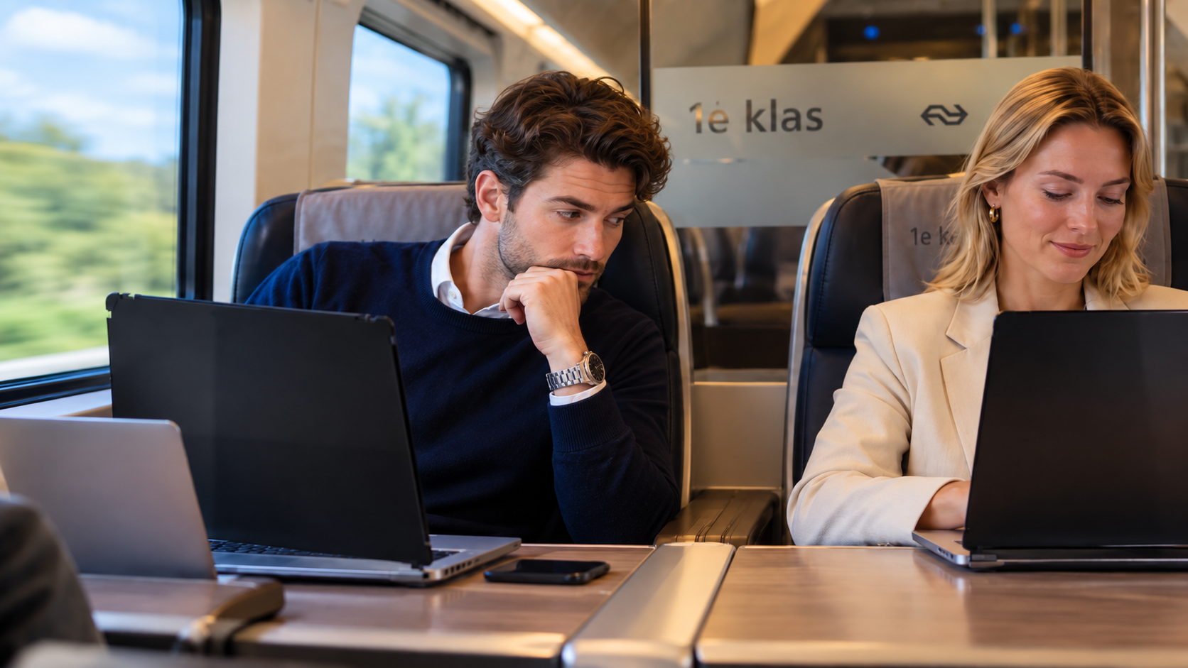 Man kijkt in de trein stiekem naar het laptopscherm van een vrouw die met een privacyfilter werkt.